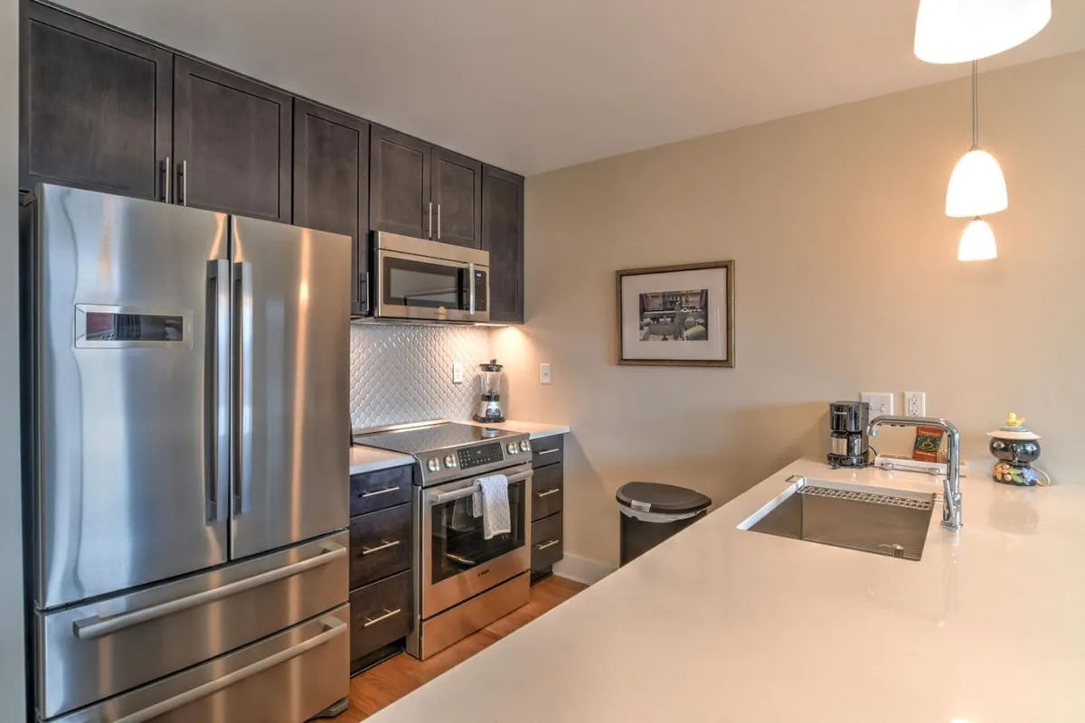 A spacious, welcoming kitchen with stainless steel appliances, a kitchen island, and framed artwork on the walls. The open layout is ideal for cooking and gathering, suggesting a homely atmosphere to return to after a day out.