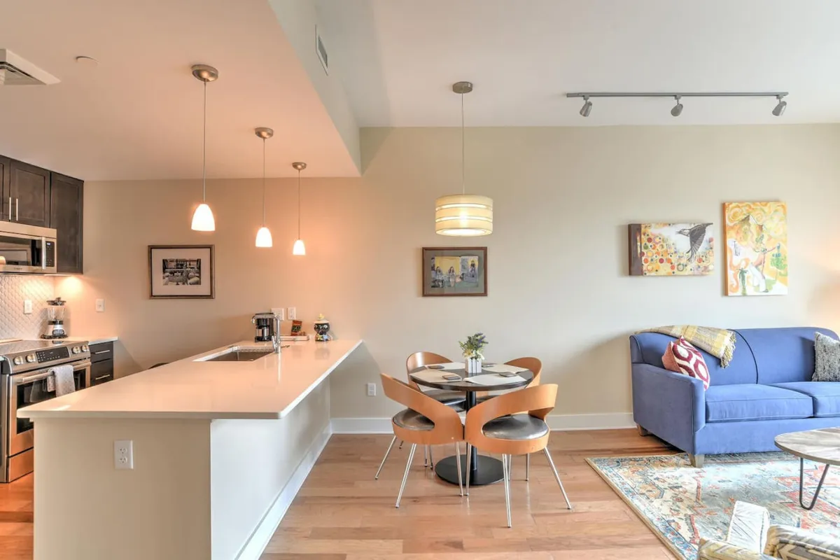 A cohesive shot of the kitchen island, dining table, and adjacent sofa, all set in a bright, contemporary space. The layout emphasizes openness and is ideal for hosting dinners or casual gatherings.