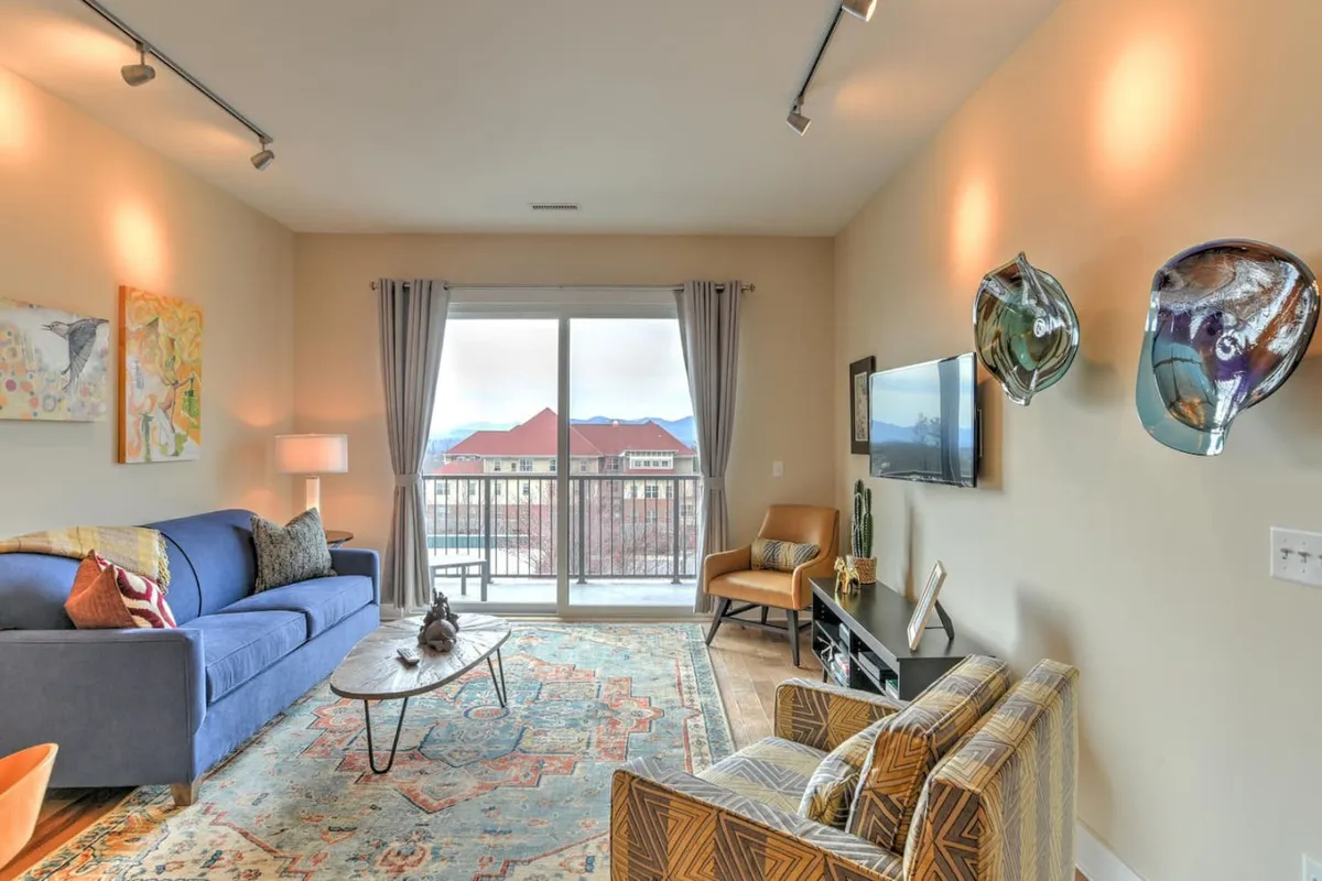 A cozy, contemporary common area featuring a sofa, armchair, coffee table, and wall artwork, with natural light flooding the space from a window. The inviting ambiance illustrates the comfort and relaxation available to guests and their pets.